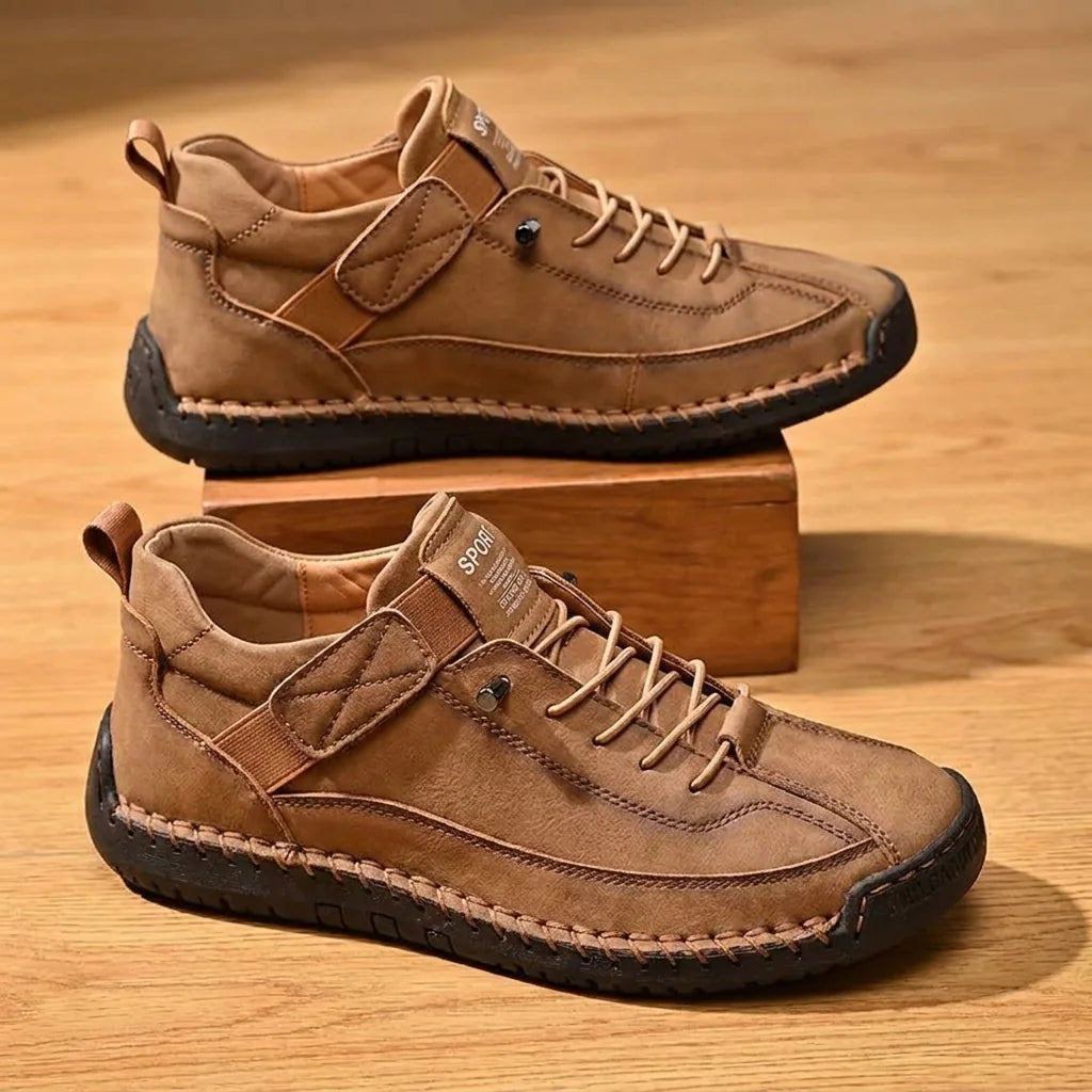 Pair of brown hand-stitched slip-on casual shoes on warm wood