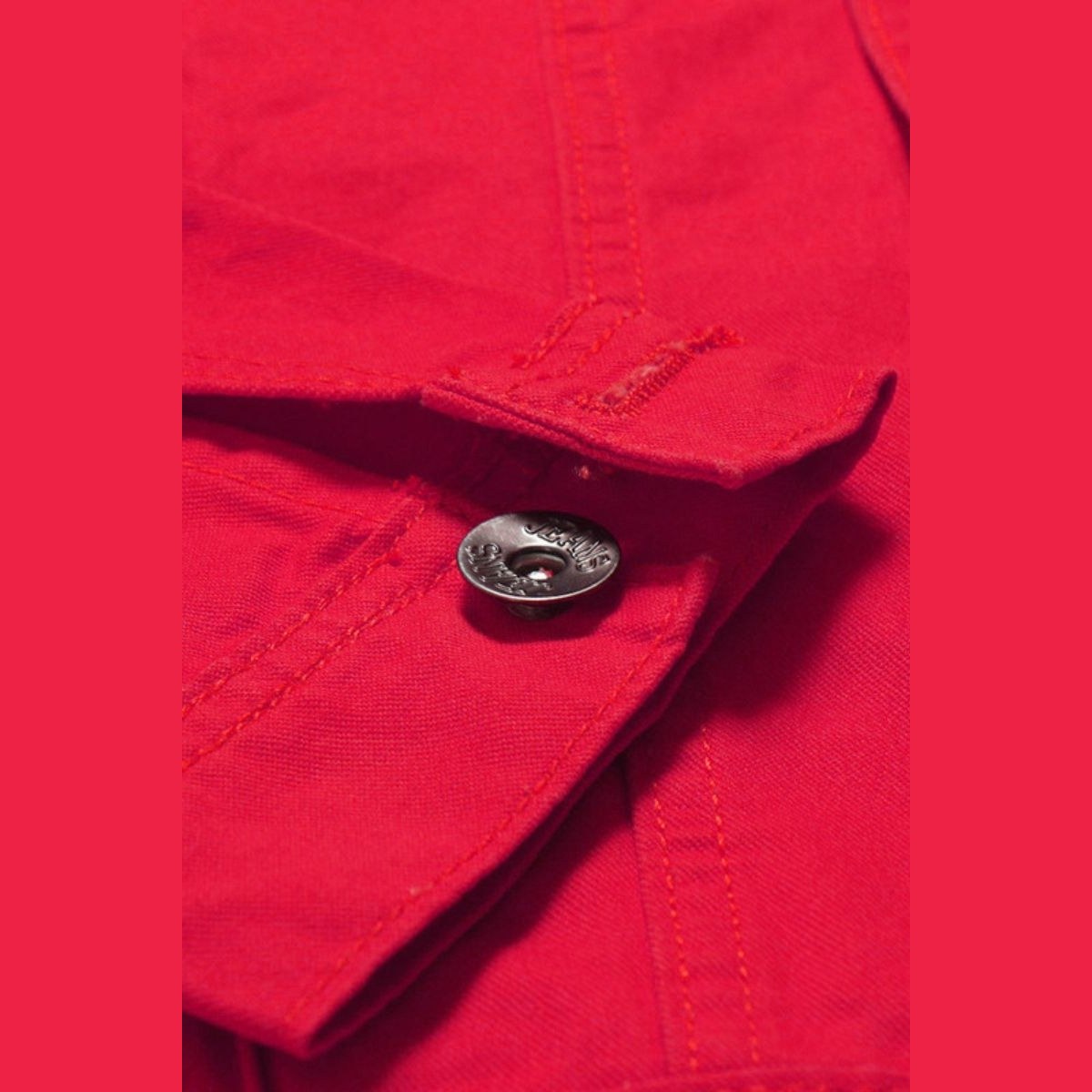Close view of a button and stitched flap on the red jacket