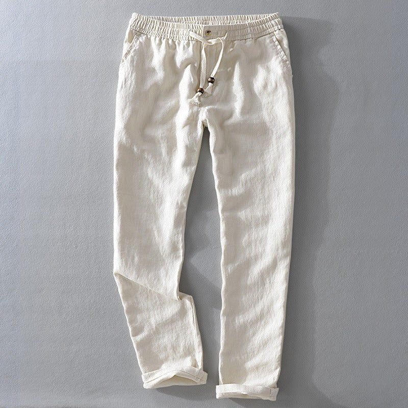 Cream drawstring pants laid flat with a rolled hem