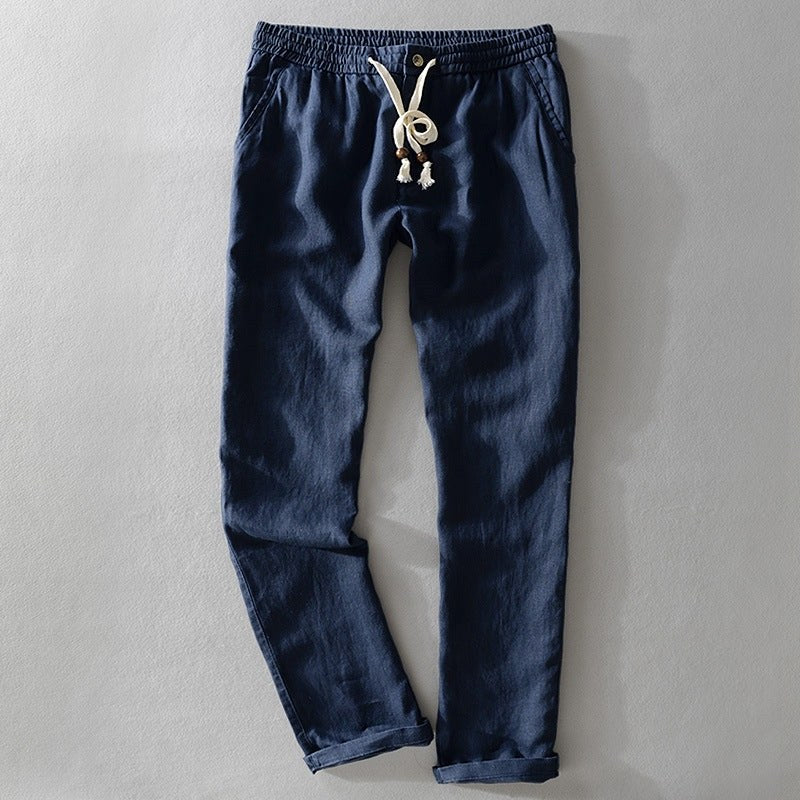 Dark blue drawstring pants laid flat with a tasselled cord