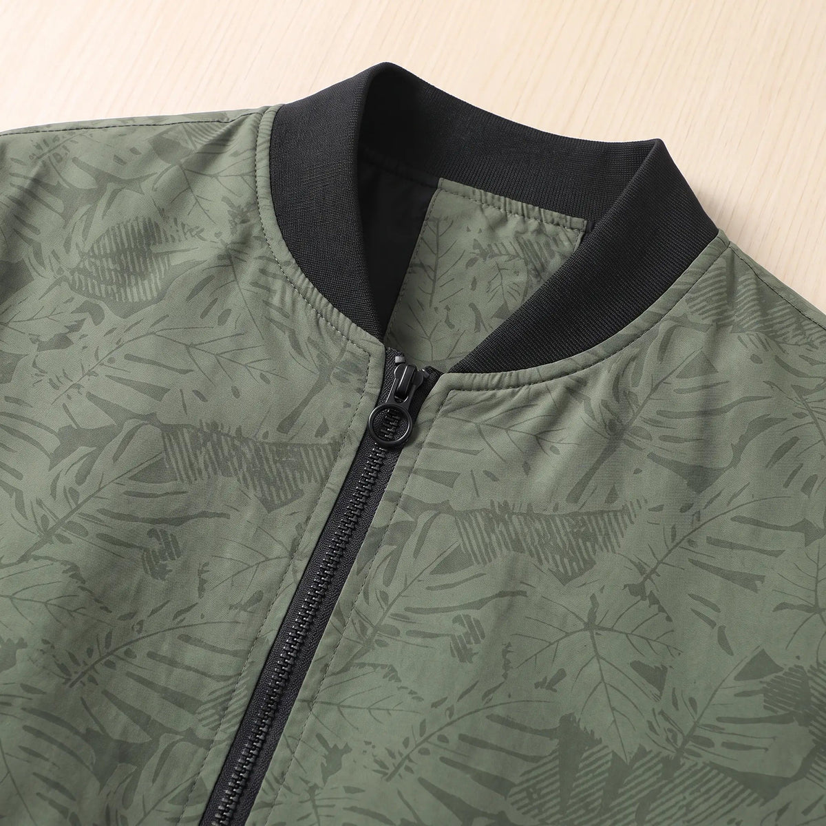 Ribbed collar and front zip of the men's leaf print bomber jacket