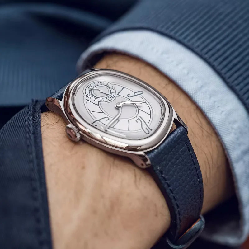 Harcourt silver-toned oval watch worn with a blue shirt cuff