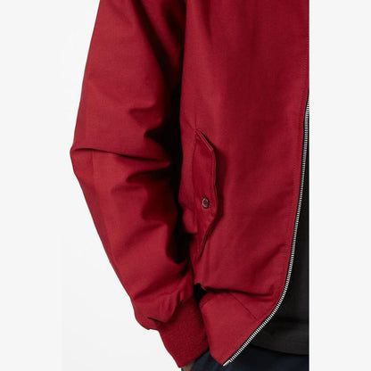 Close view of a snap flap pocket and ribbed cuff on a dark red sleeve