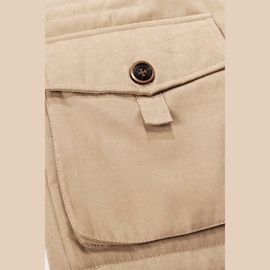 Close view of a flap pocket with a metal button on the khaki parka