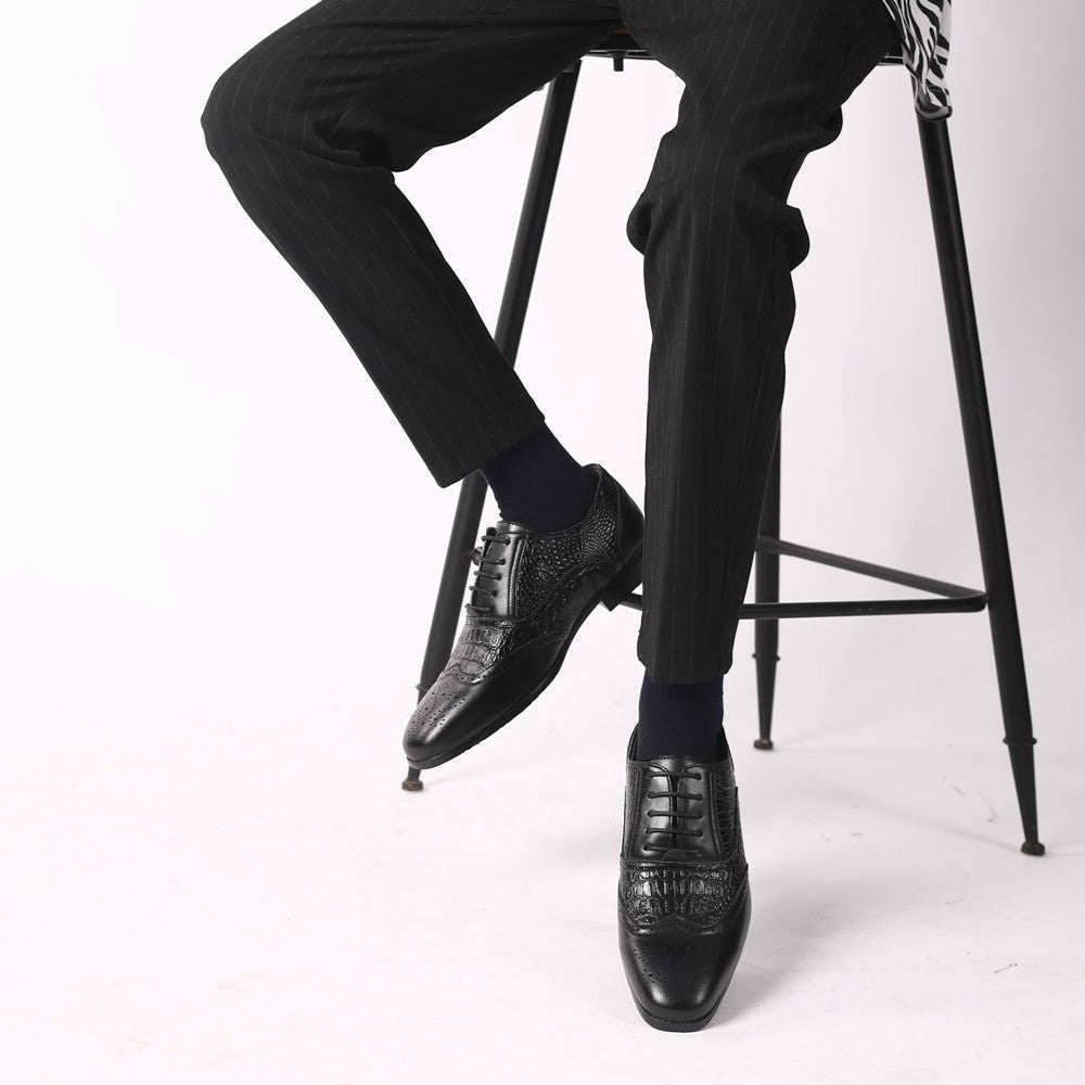 Black Kendrick brogue oxfords worn while seated on a stool