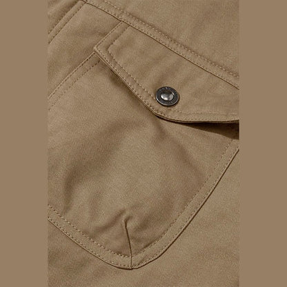 Close view of a flap pocket with a metal button on the khaki jacket