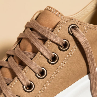 Close view of the metal eyelets and laces on the tan canvas upper
