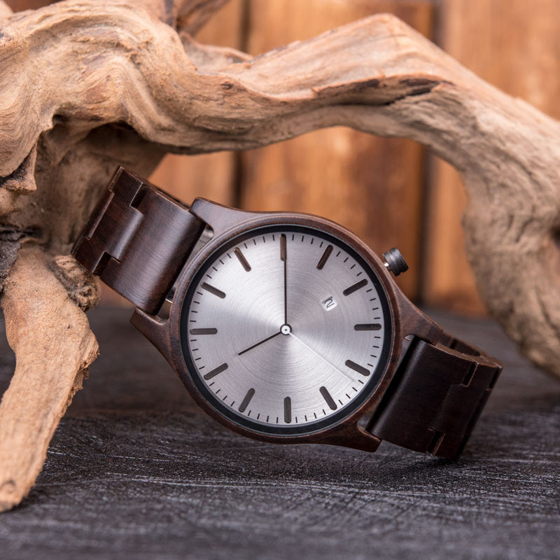 Rutledge walnut wood watch with silver dial placed beside driftwood