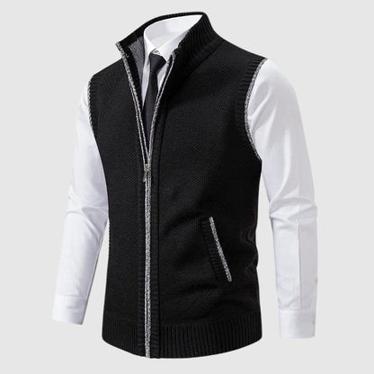 Black knit vest worn over a white shirt and tie, zipped up